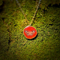 Necklace with a red pendant featuring an owl design on a green moss background