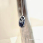 Silver earring with a dark gemstone on a neutral background