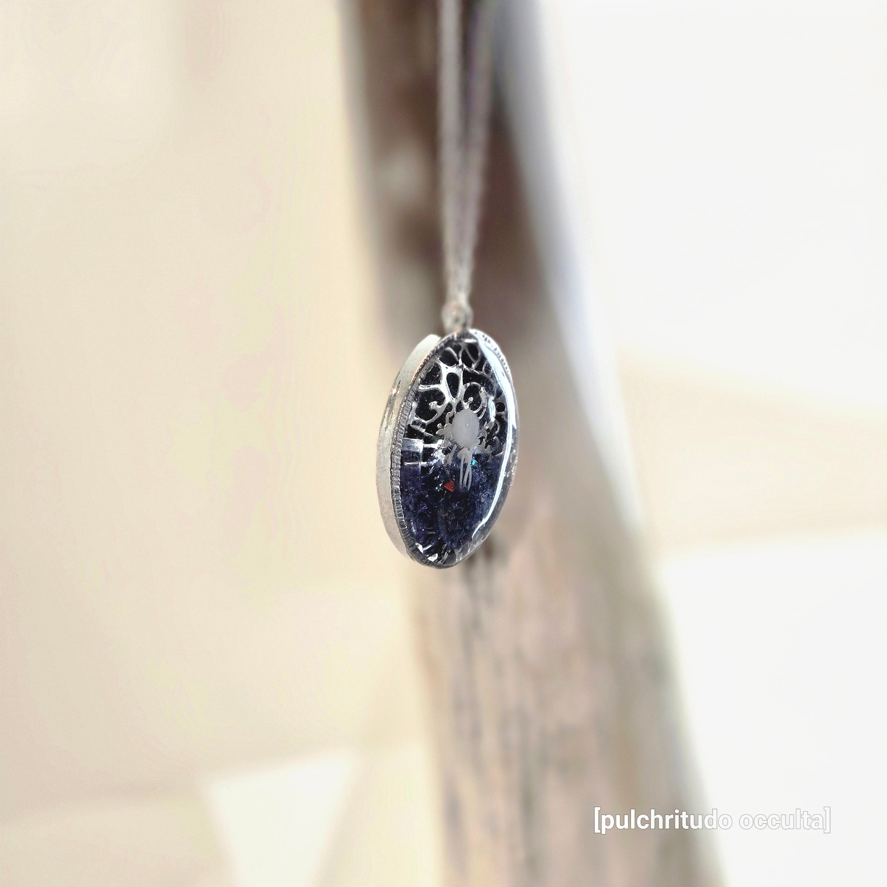 Silver earring with a dark gemstone on a neutral background