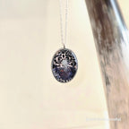 Necklace with an oval pendant featuring intricate design on a neutral background