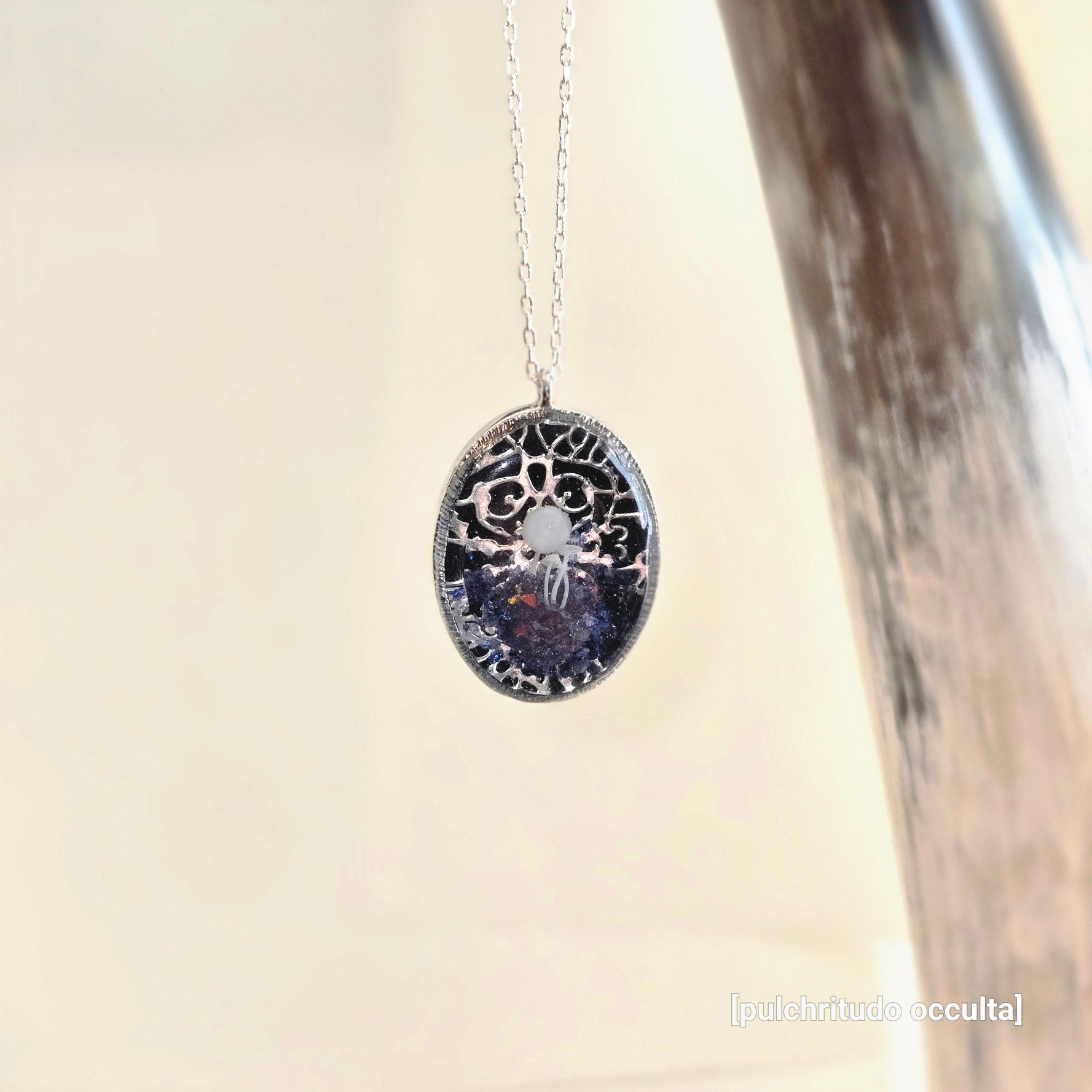 Necklace with an oval pendant featuring intricate design on a neutral background