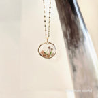 Necklace with a natural-shaped pendant featuring a floral design on a neutral background