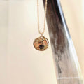 Necklace with a pendant hanging from a horn against a neutral background