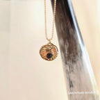 Necklace with a pendant hanging from a horn against a neutral background