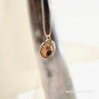 Gold necklace with a textured pendant on a blurred background