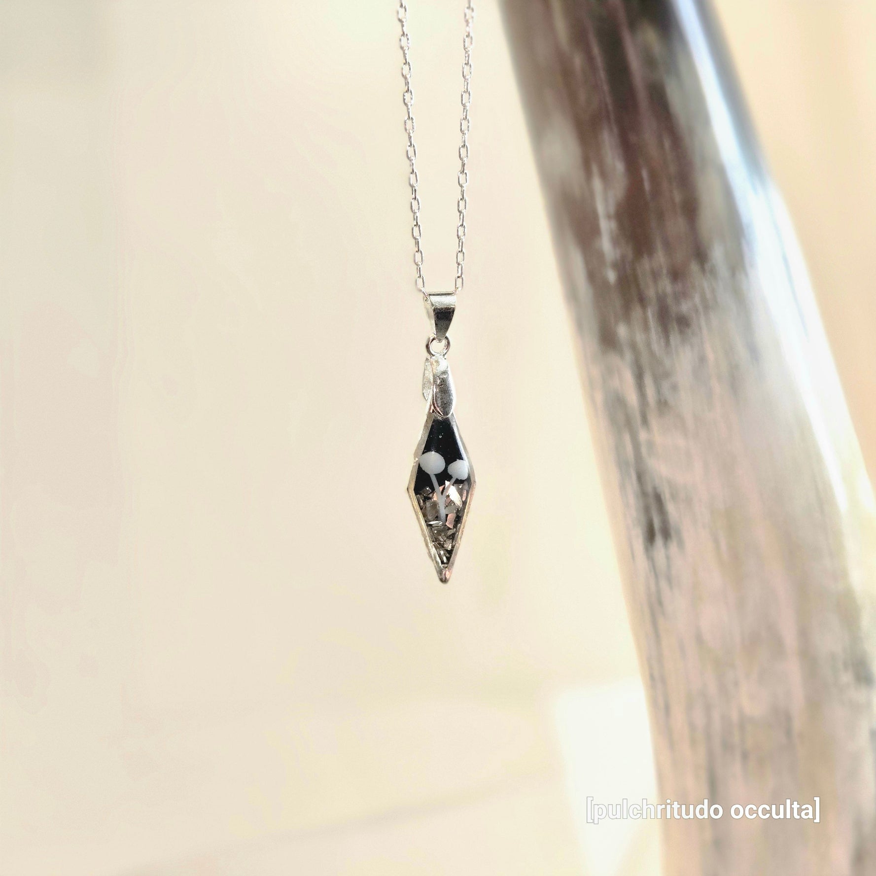 Silver necklace with a diamond shaped pendant featuring 2 small mushrooms