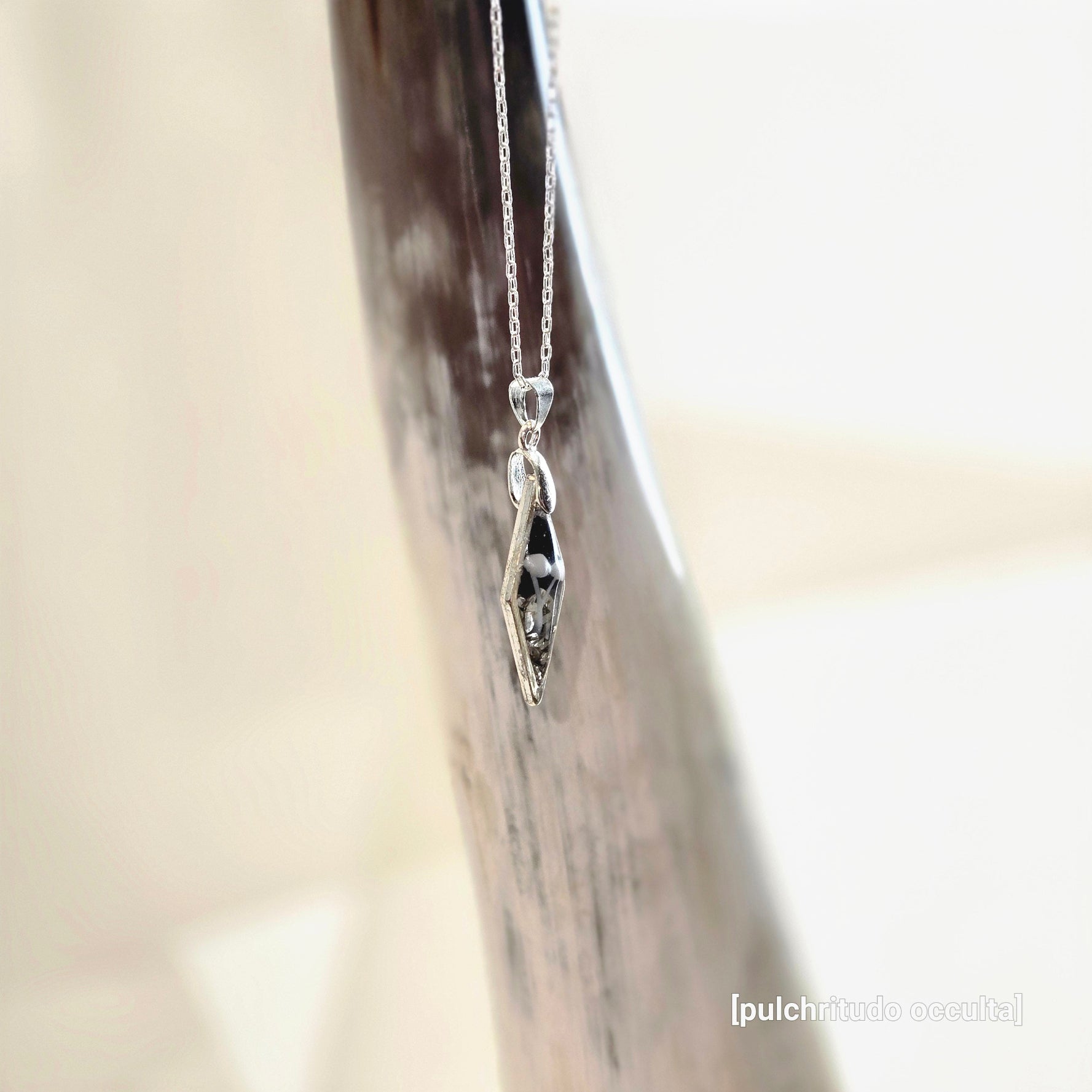 Silver necklace with a diamond shaped pendant featuring 2 small mushrooms
