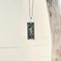 Necklace with a rectangular pendant featuring a mushroom design on a metallic background