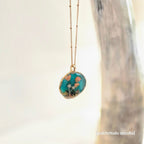 Necklace with a pendant featuring floral design on a blurred background
