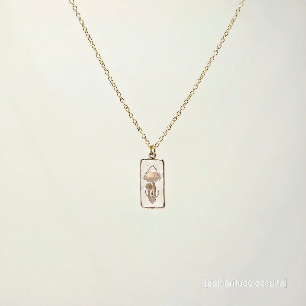 Gold necklace with a pendant on a light beige background