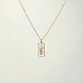 Gold necklace with a pendant on a light beige background