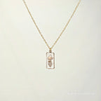 Gold necklace with a pendant on a light beige background