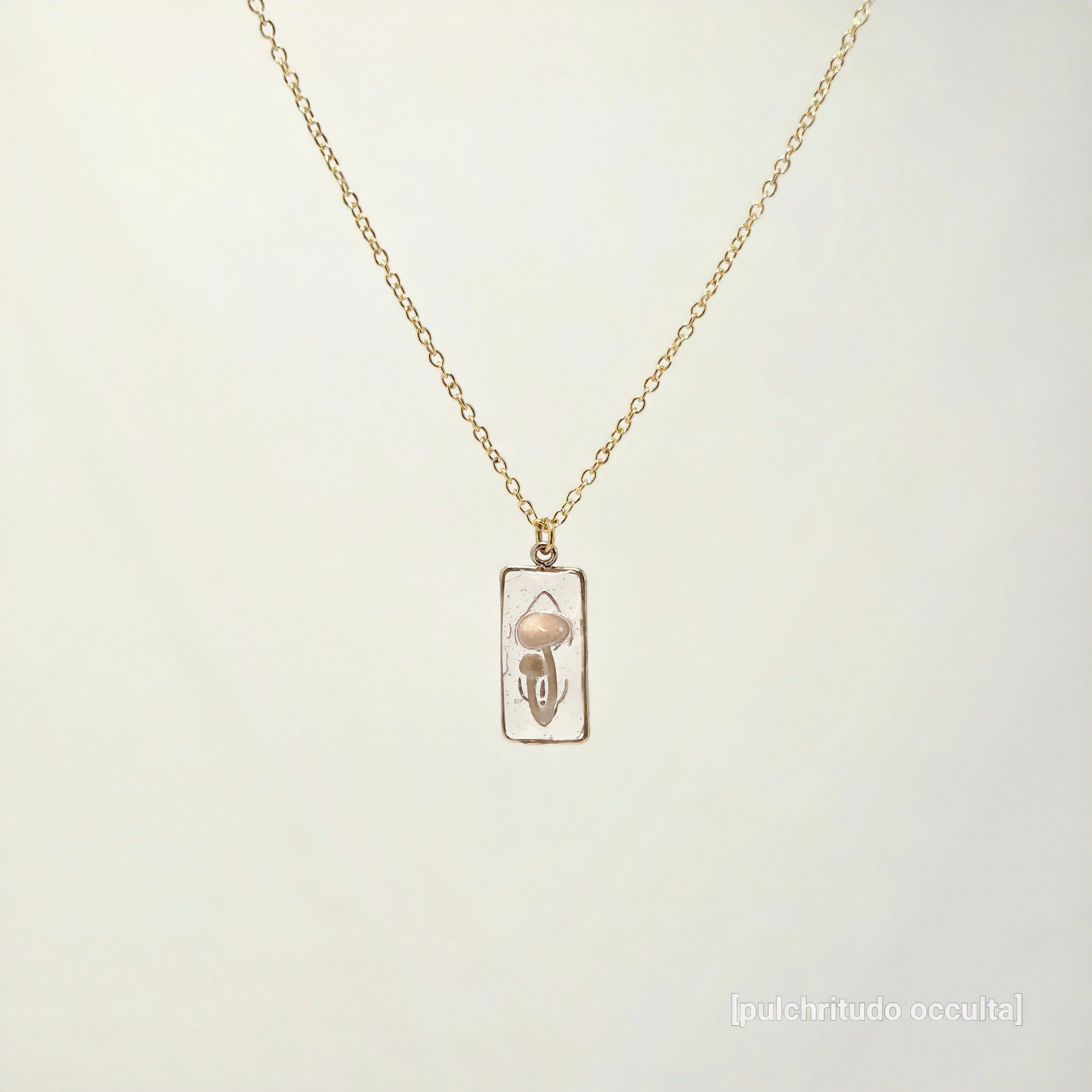 Gold necklace with a pendant on a light beige background