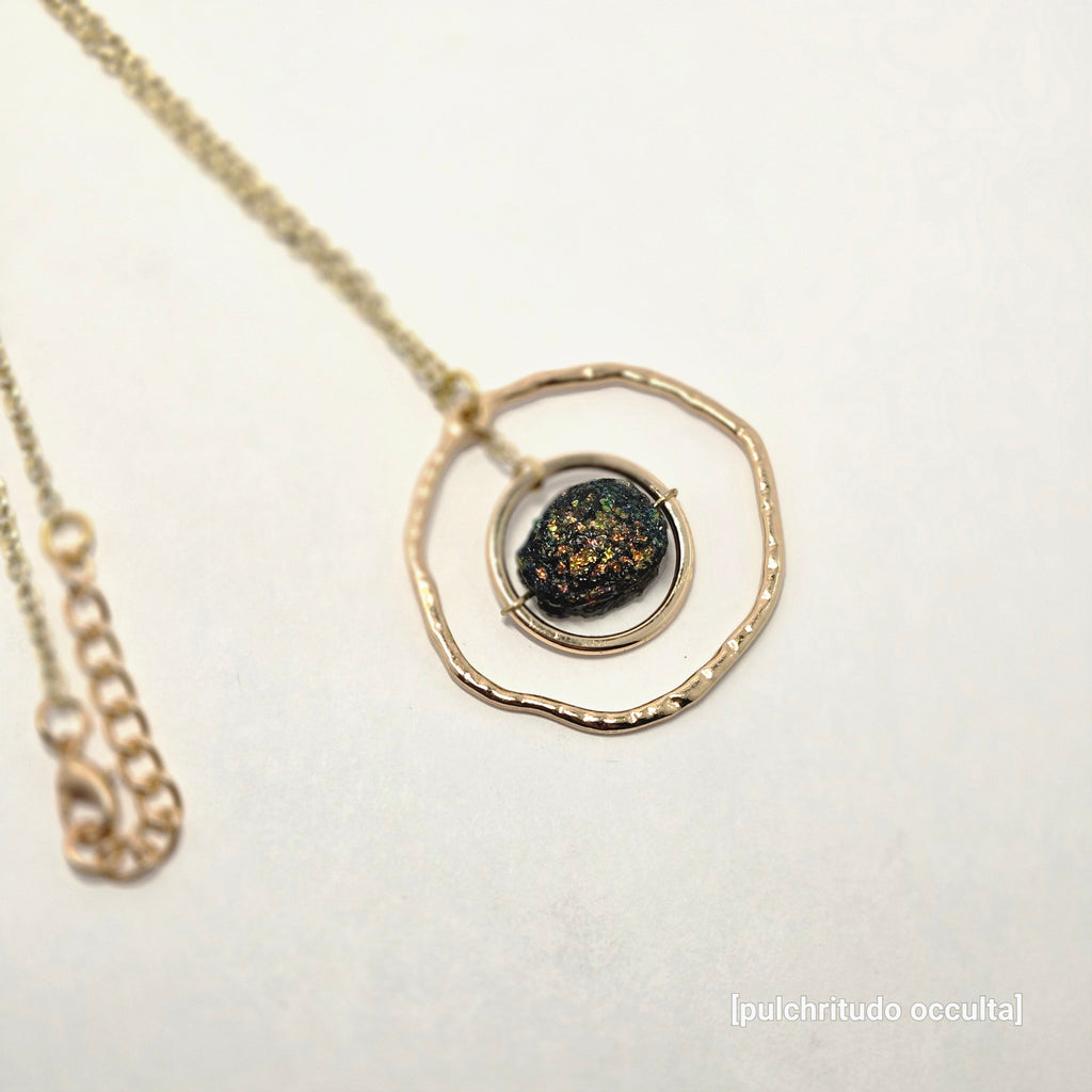 Necklace with a gold pendant featuring a dark stone on a light background
