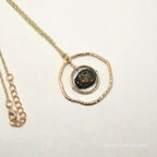 Necklace with a gold pendant featuring a dark stone on a light background