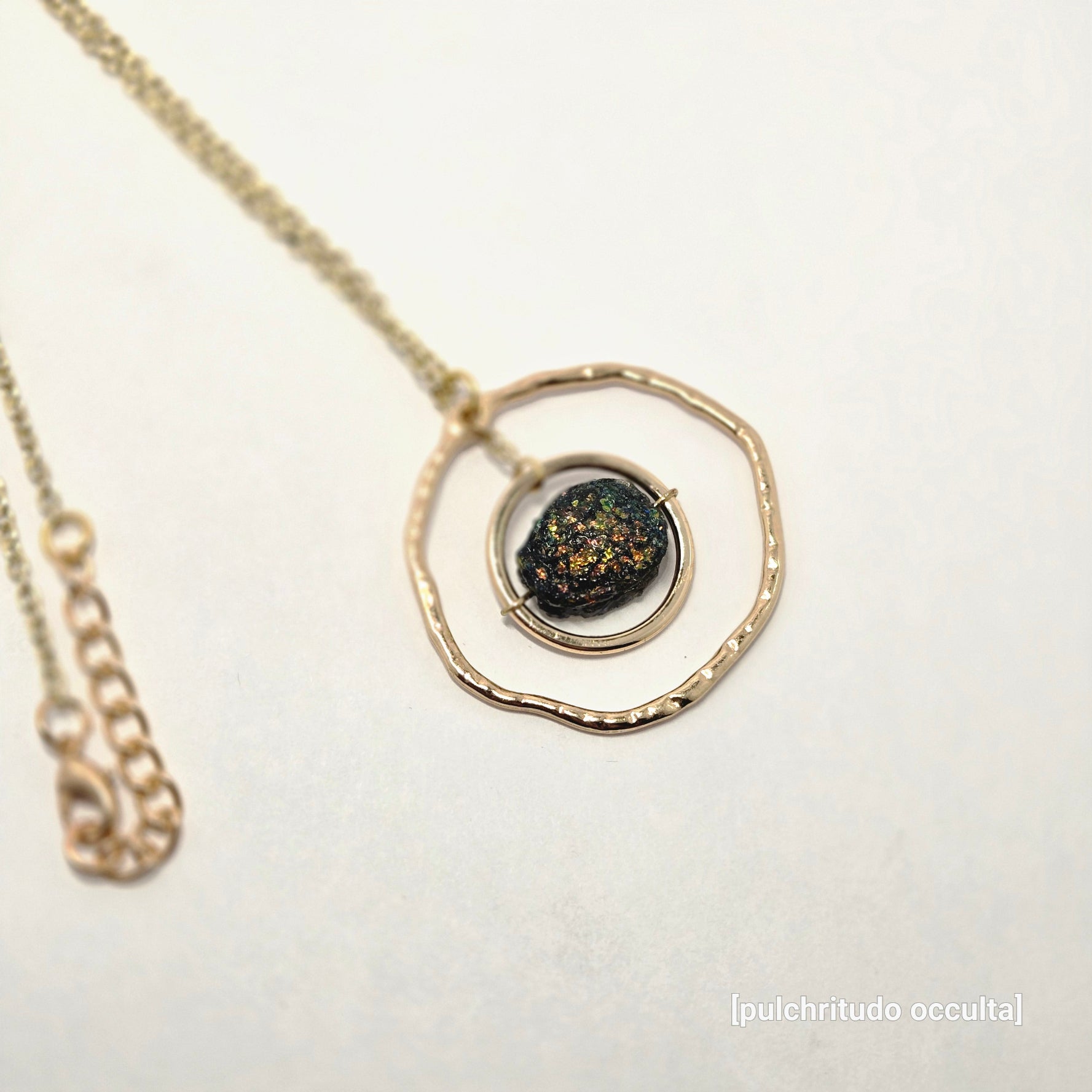 Necklace with a gold pendant featuring a dark stone on a light background