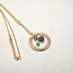 Gold necklace with a round pendant on a white background