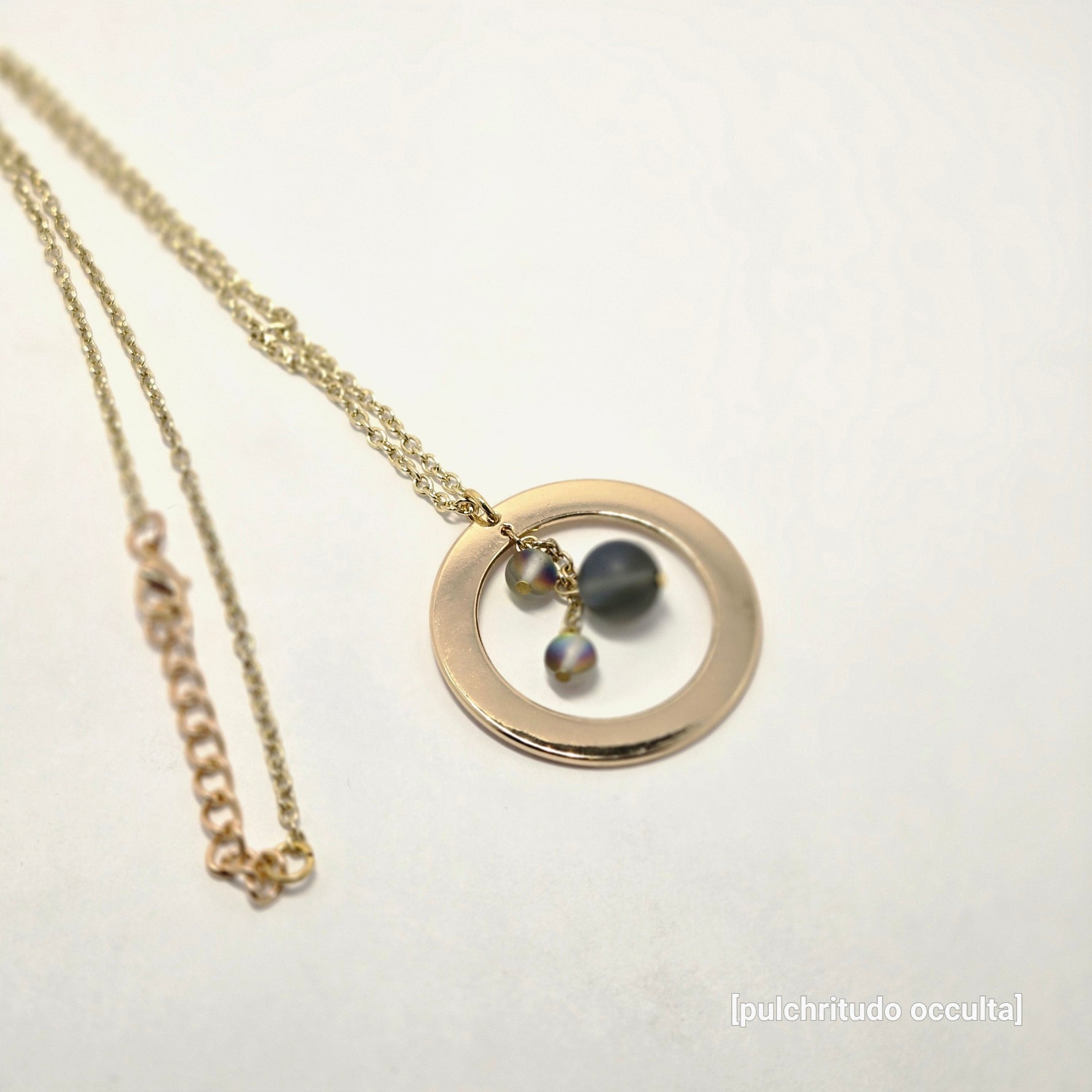 Gold necklace with a round pendant on a white background