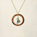 Necklace with a gold ring pendant featuring two small stones on a beige background
