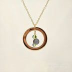 Necklace with a gold ring pendant featuring two small stones on a beige background