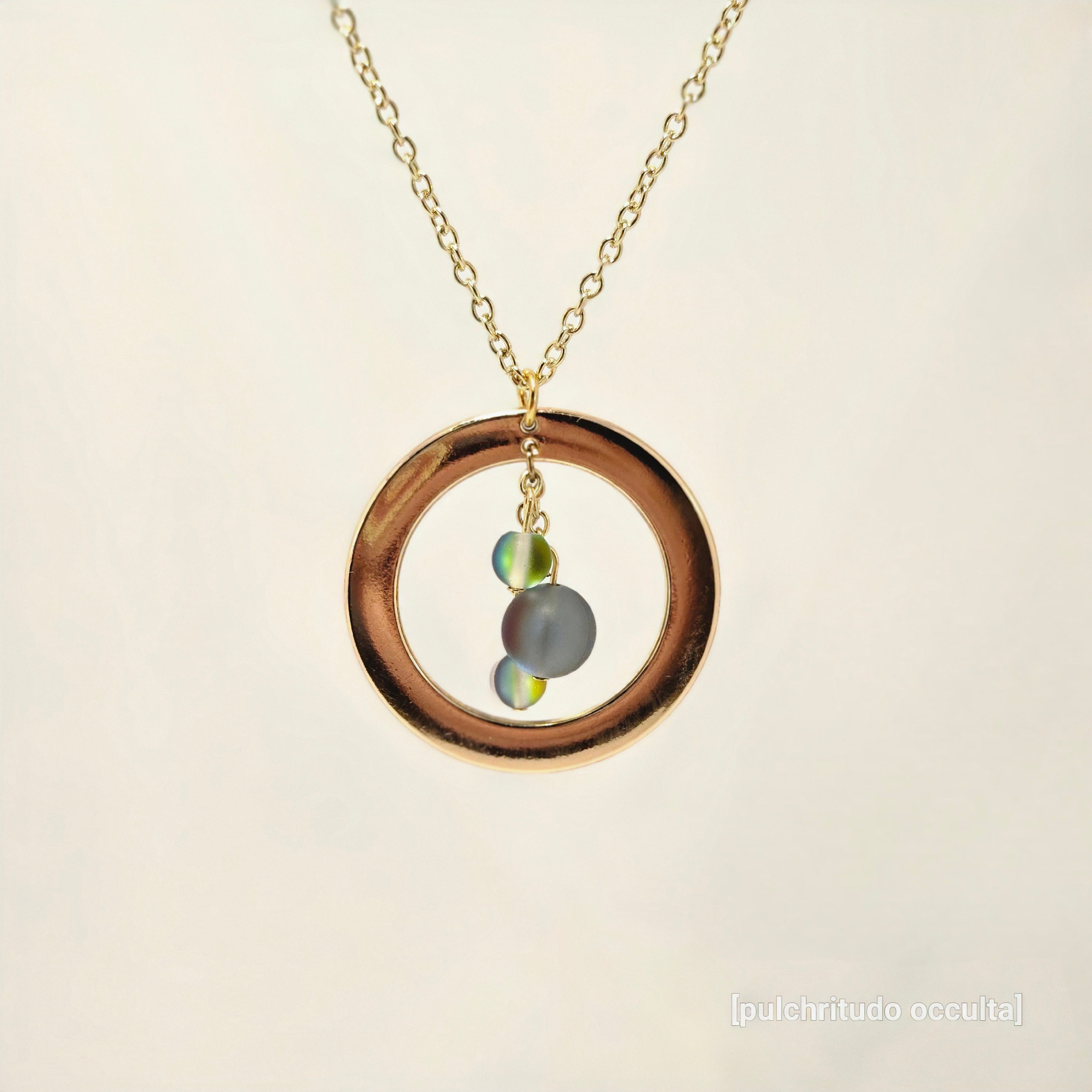 Necklace with a gold ring pendant featuring two small stones on a beige background