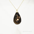 Teardrop-shaped pendant with mechanical design on a white background