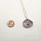 Necklace with a pendant next to a penny on a white background