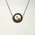 Necklace with a round pendant featuring a mushroom and fern on a white background