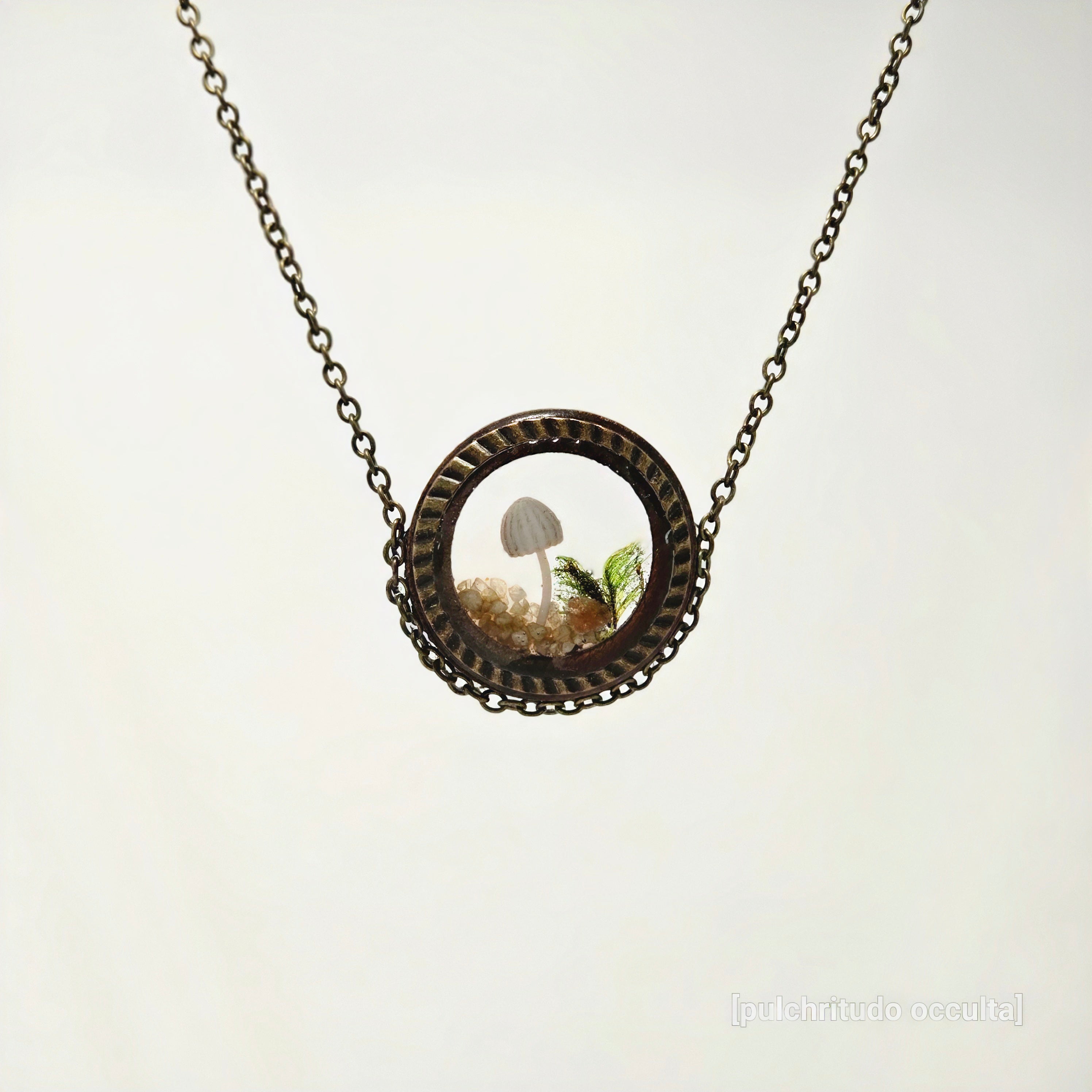 Necklace with a round pendant featuring a mushroom and fern on a white background