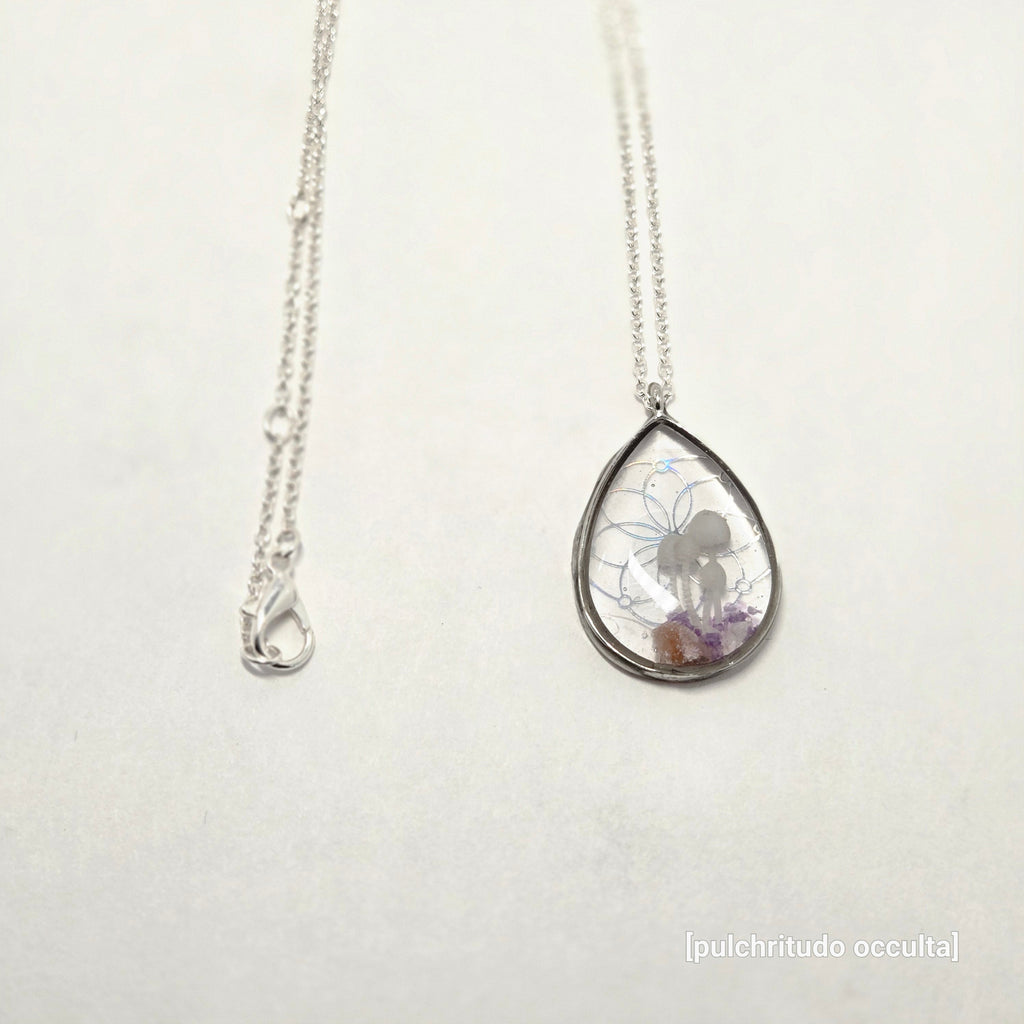 Silver necklace with a teardrop-shaped pendant on a light gray background