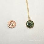 Small green pendant necklace on a white background with a penny for scale.
