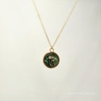 Necklace with a round pendant featuring a floral design on a light background