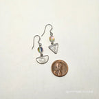 Small silver earrings with colorful stones next to a penny on a white background