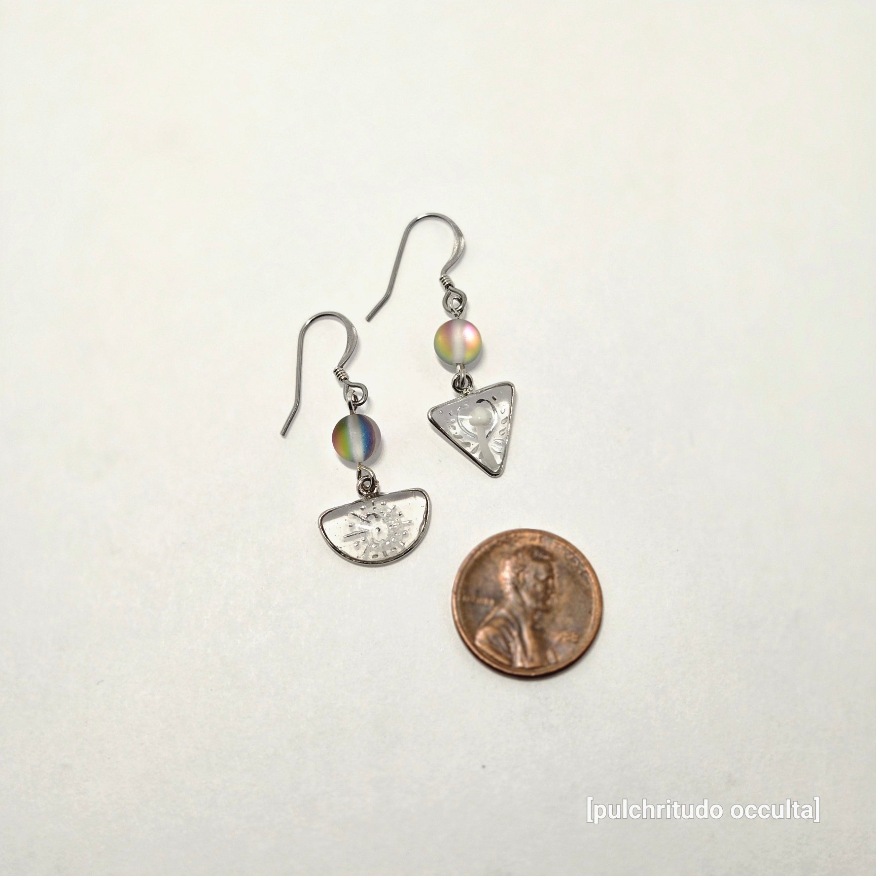 Small silver earrings with colorful stones next to a penny on a white background