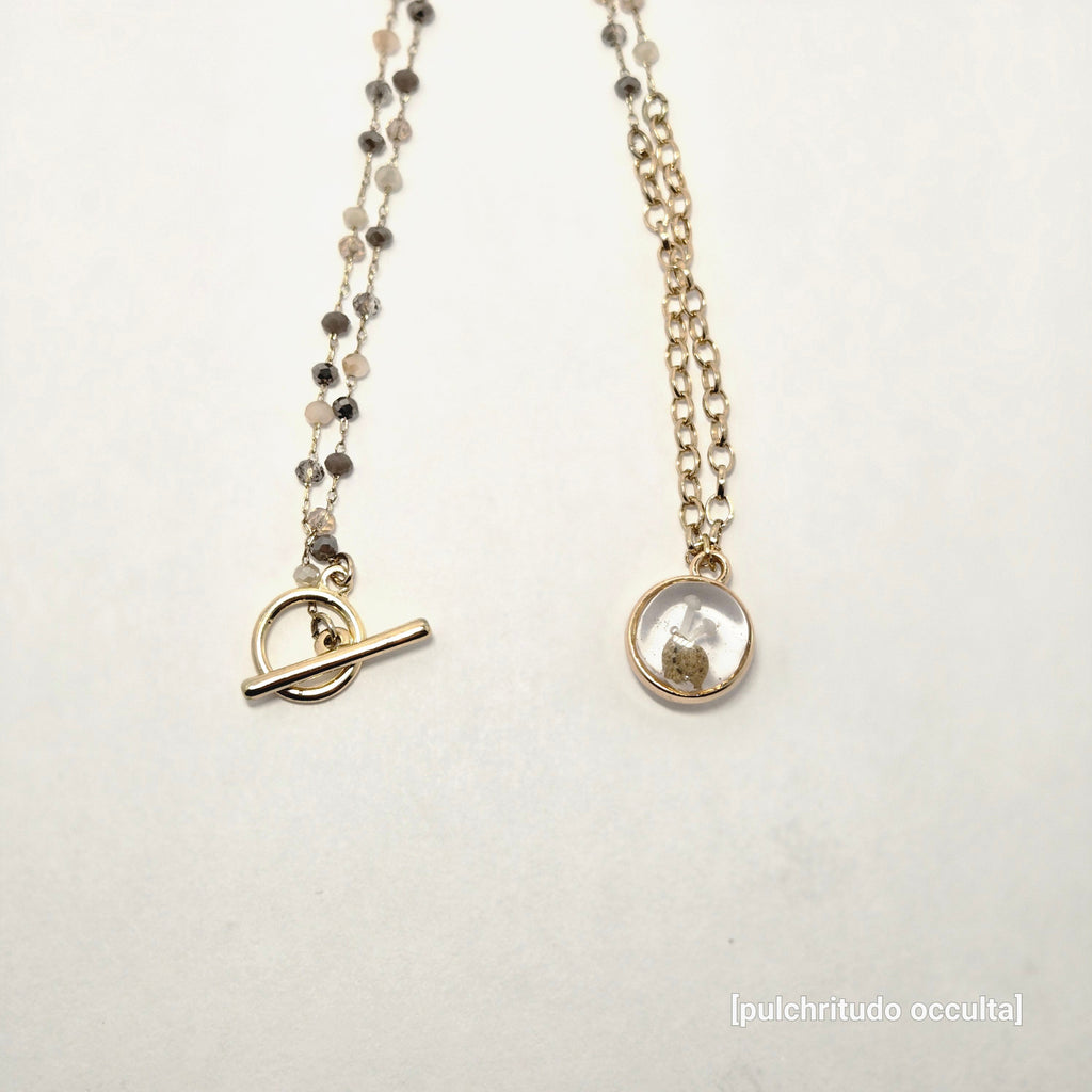 necklace on a light gray background with 'puichritud oculta' branding.