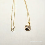 Gold necklace with a circular pendant on a white background