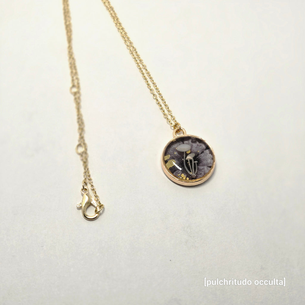 Necklace with a round pendant featuring a skeleton hand design on a light gray background.
