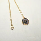 Necklace with a round pendant featuring a skeleton hand design on a light gray background.