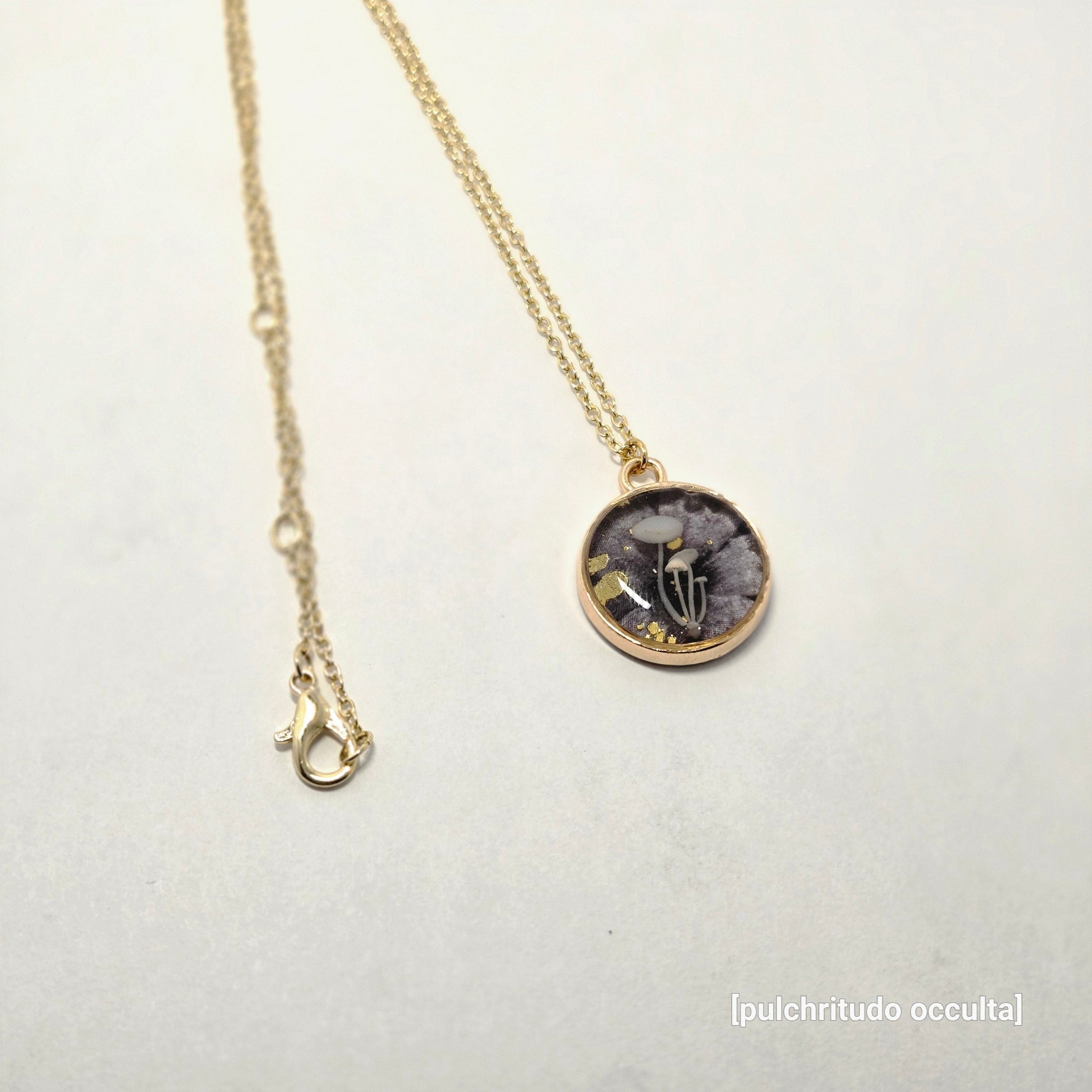 Necklace with a round pendant featuring a skeleton hand design on a light gray background.