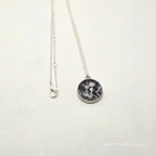 Silver necklace with a round pendant on a white background