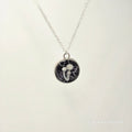 Necklace with a round pendant featuring a black and white design on a light gray background.
