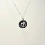 Necklace with a round pendant featuring a black and white design on a light gray background.