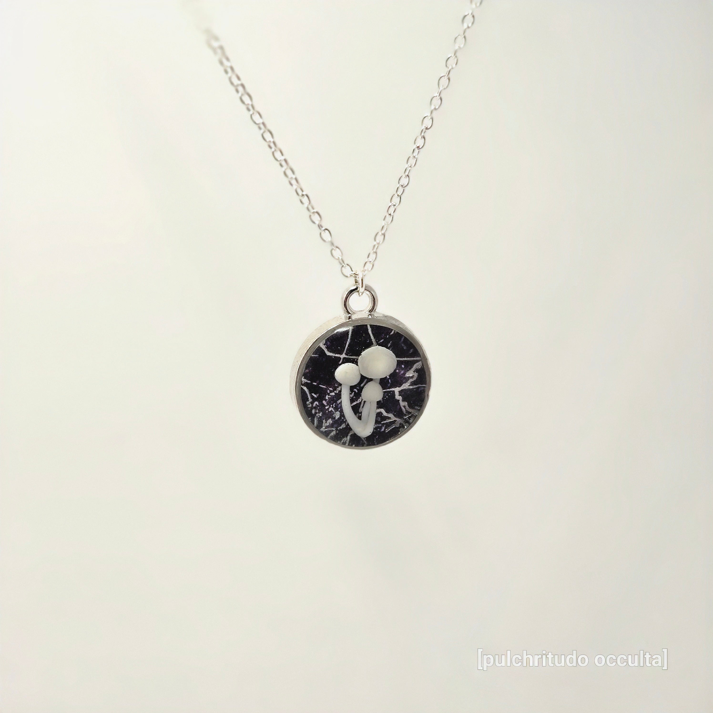 Necklace with a round pendant featuring a black and white design on a light gray background.