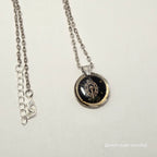 Silver necklace with a round pendant on a light gray background