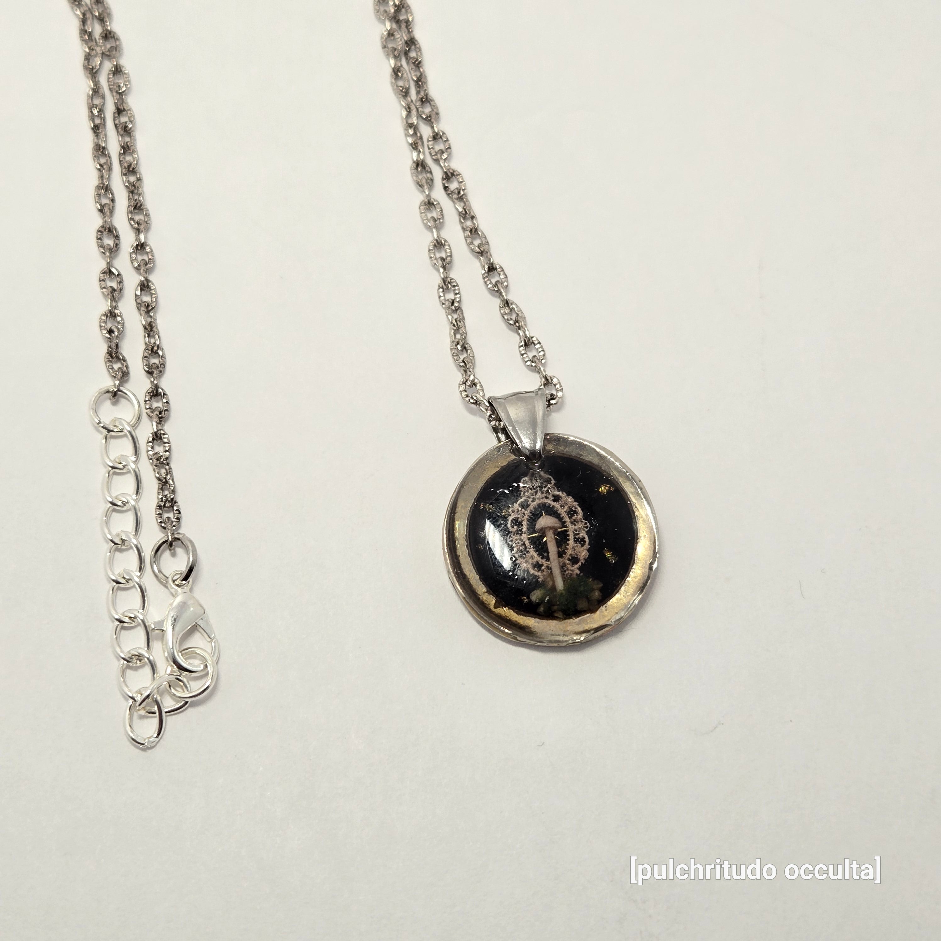 Silver necklace with a round pendant on a light gray background