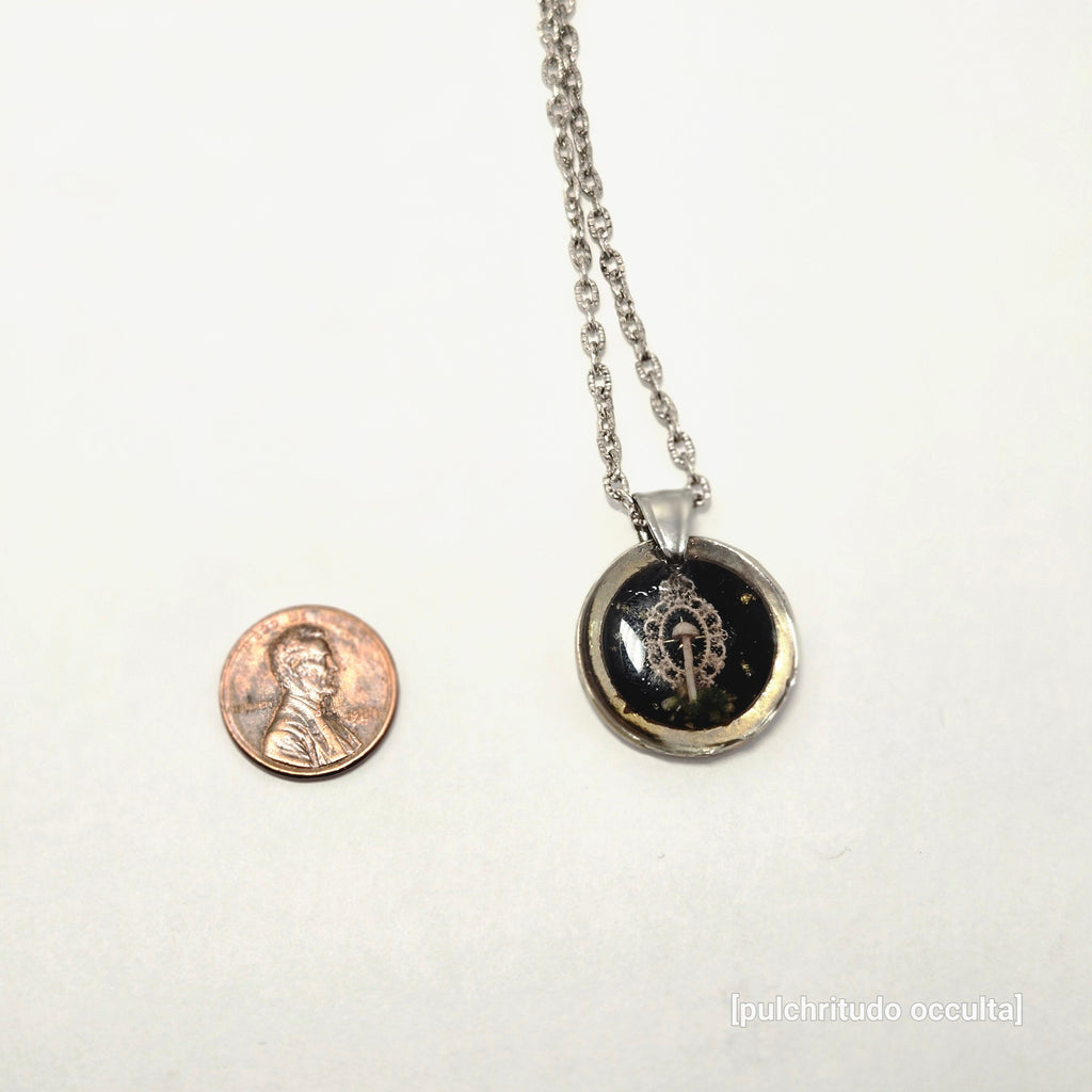 Necklace with a pendant next to a penny on a white background
