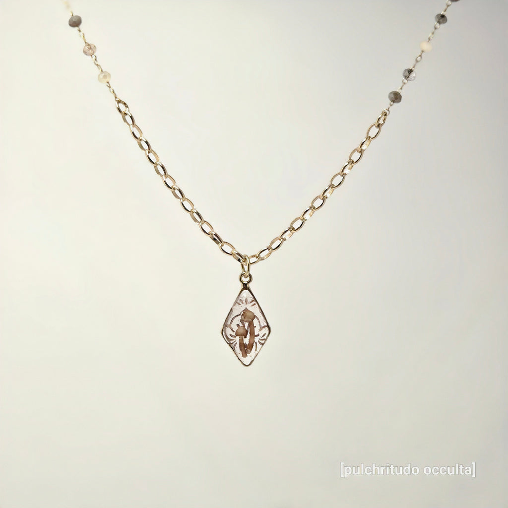 Gold necklace with a pendant on a light gray background