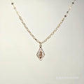 Gold necklace with a pendant on a light gray background