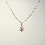 Gold necklace with a pendant on a light gray background
