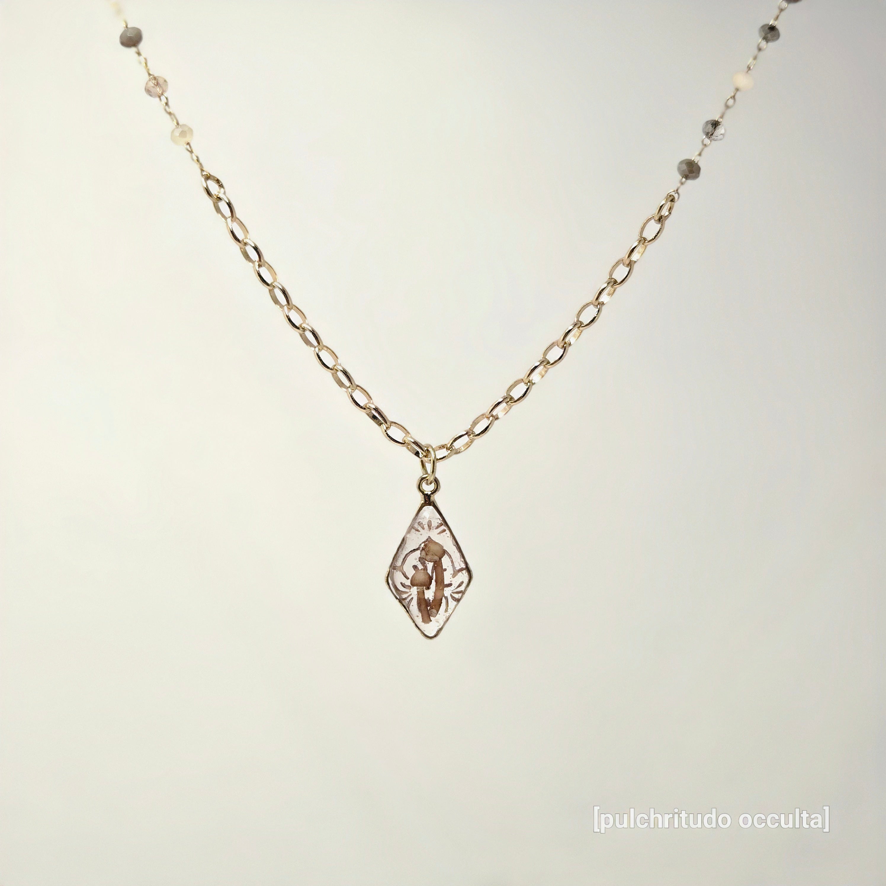 Gold necklace with a pendant on a light gray background